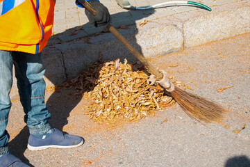 Autumn work in the park. Cleaning of fallen leaves.Cleaners clean the street from the fallen leaves...