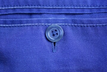 one blue plastic button on the pocket of a cloth garment