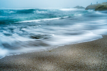 Waves at the beach on the sand, overcast day