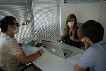 Naklejka premium Teamwork Of Business People During Pandemic Of Coronavirus, Colleagues In Protective Masks Communicate Sitting At Negotiating Table In Office, Selective Focus On Smiling Woman Using Computer