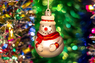 Vintage old Soviet Christmas tree toy (snowman) on the background of a Christmas tree and New Year's multi-colored tinsel.