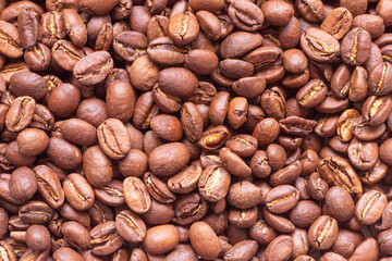 Roasted arabica coffee beans scattered in a heap on the table.