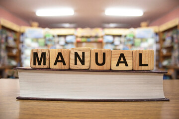 Manual words on wooden blocks on book with bluered backround