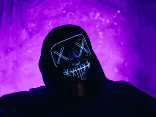 Halloween party incognito in a glowing mask portrait . Purple shades background