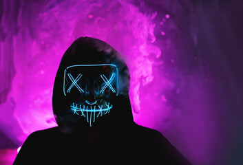 Halloween party incognito in a glowing mask portrait . Purple shades background