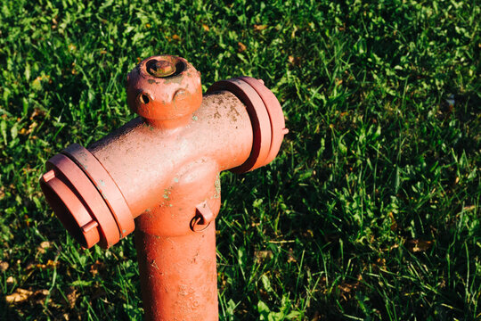 Red paint fire hydrant. Green grass empty copy space. Fire department water supply for emergency. Old peeling paint grunge metal valve that needs replacement.