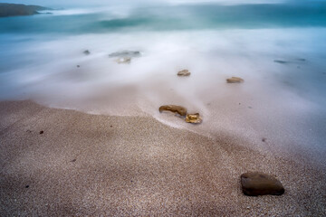 Fototapeta na wymiar Footprints on the Beach, Waves, Cloudy Day