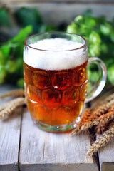 A glass of wheat beer on a wooden surface. Wheat and hops. Beer concept.