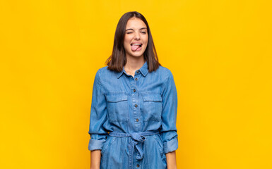 young pretty woman with cheerful, carefree, rebellious attitude, joking and sticking tongue out,...