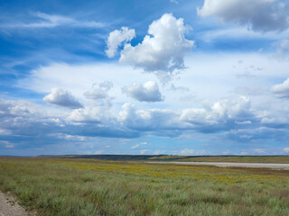 Fototapeta premium Rural landscape of blue sky in white clouds in the steppe. Dry and salt-covered Kuyalnitsky estuary near Odessa on a hot summer day