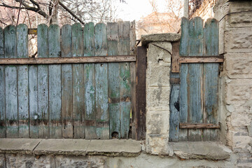 Old wooden fence, a gate with the remains of peeling blue paint. Rural landscape.