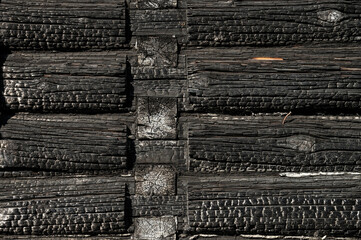 Texture (background, pattern) of a black charred log wall of a burned-out wooden house.