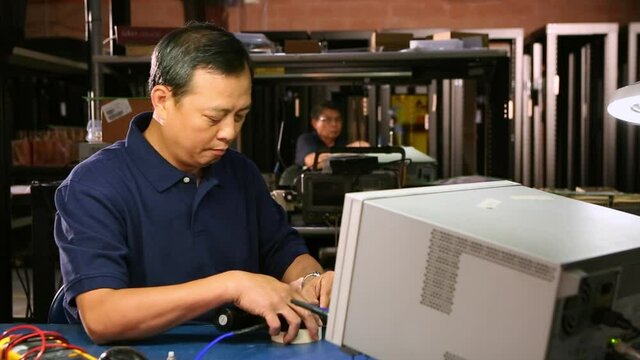 Asian electrical engineer testing computer component