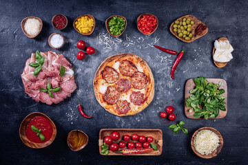 Pizza with ingredients on dark table