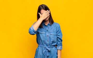 young pretty woman looking stressed, ashamed or upset, with a headache, covering face with hand