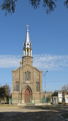 Vista de una Iglesia de la década de 1930, con ladrillos en el exterior, con su nuevo campanario y una cruz en el el extremo superior.