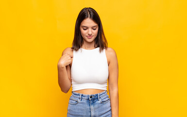 young pretty woman smiling cheerfully and casually, looking downwards and pointing to chest