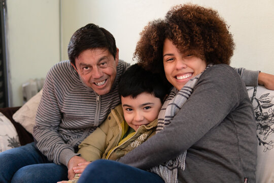 Happy Cheerful Brazilian Multigenerational Family Sitting In Sofa Embracing Each Other Indoors At Home Living Room. Affectionate, Bonding, Love, Generation Concept.