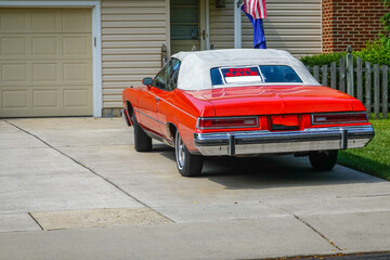 Red old historic car parked in a driveway with a white convertible roof has a for sale sign in its...