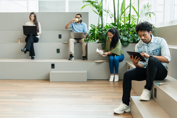 Serious latin male entrepreneur with tablet focused on working in office workspace Collaboration, creative, discussion, meeting concept..