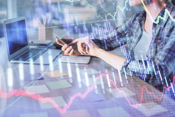 Double exposure of businesswoman hands typing on computer and forex graph hologram drawing. Financial analysis concept.