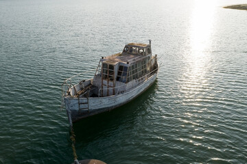 Obraz premium Muted shades. A small old wooden fishing boat sways on the waves at the pier.