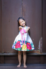 cute little asian girl in dress holding a gift in home
