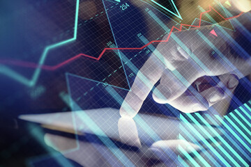 Double exposure of man's hands holding and using a digital device and forex graph drawing. Financial market concept.