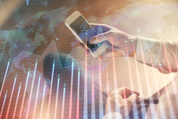 Double exposure of man's hands holding and using a digital device and forex graph drawing. Financial market concept.