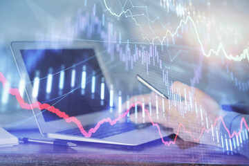 Double exposure of man's hands holding and using a digital device and forex graph drawing. Financial market concept.