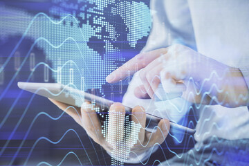 Double exposure of man's hands holding and using a digital device and forex graph drawing. Financial market concept.