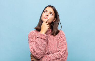 young pretty woman feeling thoughtful, wondering or imagining ideas, daydreaming and looking up to...