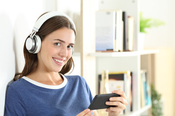 Happy teen with phone and headphones looks at you