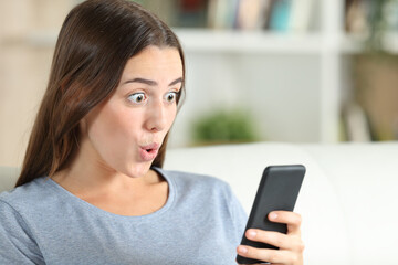 Fototapeta na wymiar Surprised girl checks smart phone at home