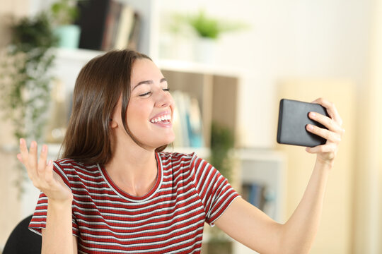 Happy teen talking in a video call on phone at home