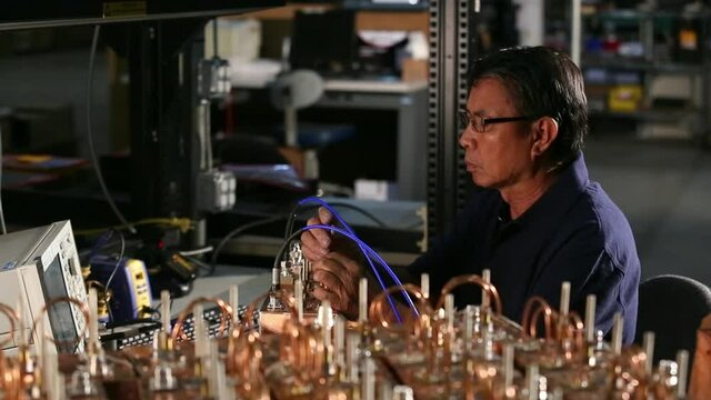 Asian electrical engineer with tools testing computer component