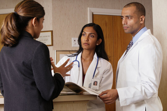 Doctors and businesswoman examining a brochure