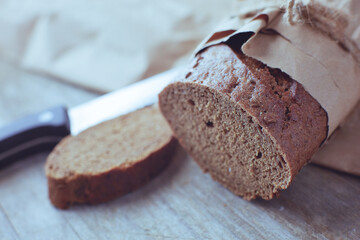 A loaf of Bread packed in paper on wooden table.