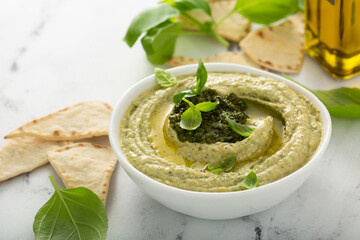 Basil hummus topped with pesto and served with pita chips