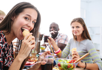 Top view of group of people having dinner together while sitting at wooden table. Food on the table. People eat fast food.