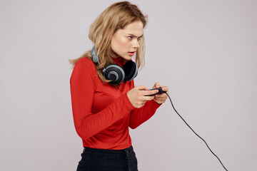 Woman with headphones controller in hands a console game fun leisure red jacket lifestyle light background