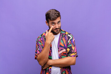 young man keeping an eye on you, not trusting, watching and staying alert and vigilant