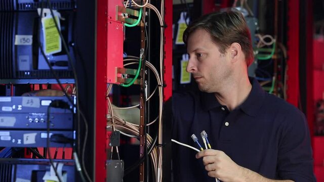 Caucasian technician connecting cables to server rack
