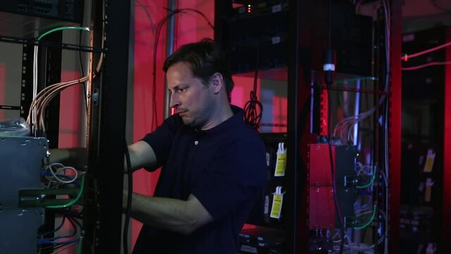 Caucasian technician connecting cables to server rack