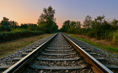 Obraz premium Rail track in landscape with colorful sky and sunset on a beautiful summer evening 