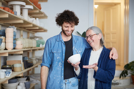 Smiling man and woman looking at bowl in pottery class
