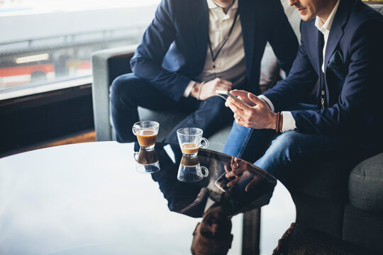 Businessman showing laptop to colleague while sitting on sofa at workplace