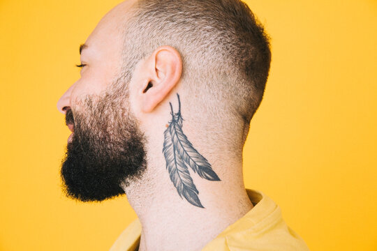 Close-up of neck tattoo on man against colored background
