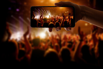Silhouette of hand using camera phone to take pictures and videos at pop concert, festival