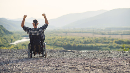 Young retired military man in a wheelchair enjoying the fresh air on a sunny day on the mountain.